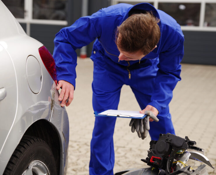 Gutachter inspiziert ein Auto mit Unfallschaden