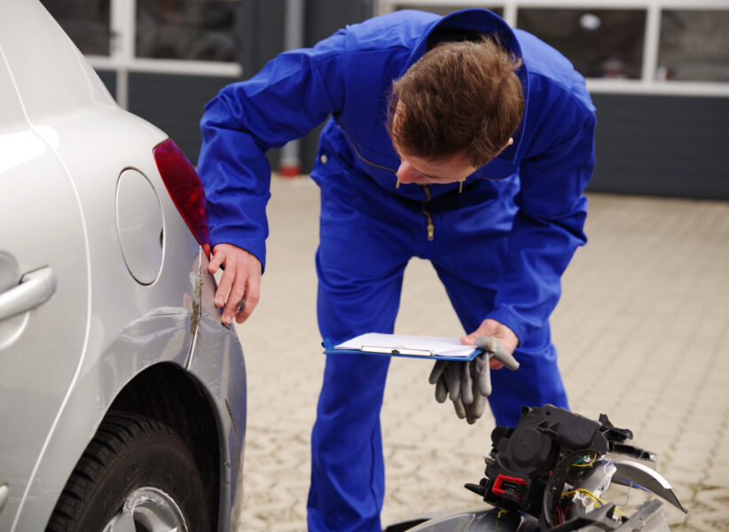 Gutachter inspiziert ein Auto mit Unfallschaden